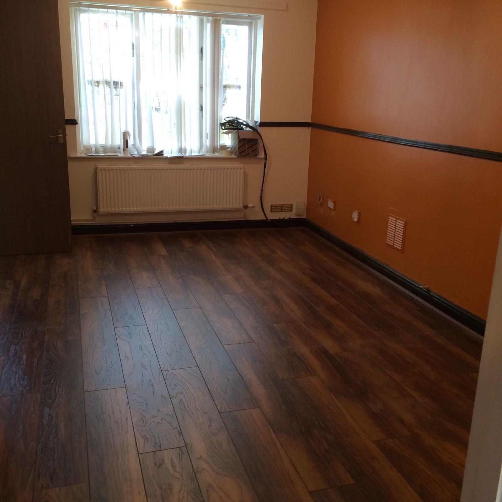 Living room with a burnt-orange feature wall above a dado rail and dark laminate flooring