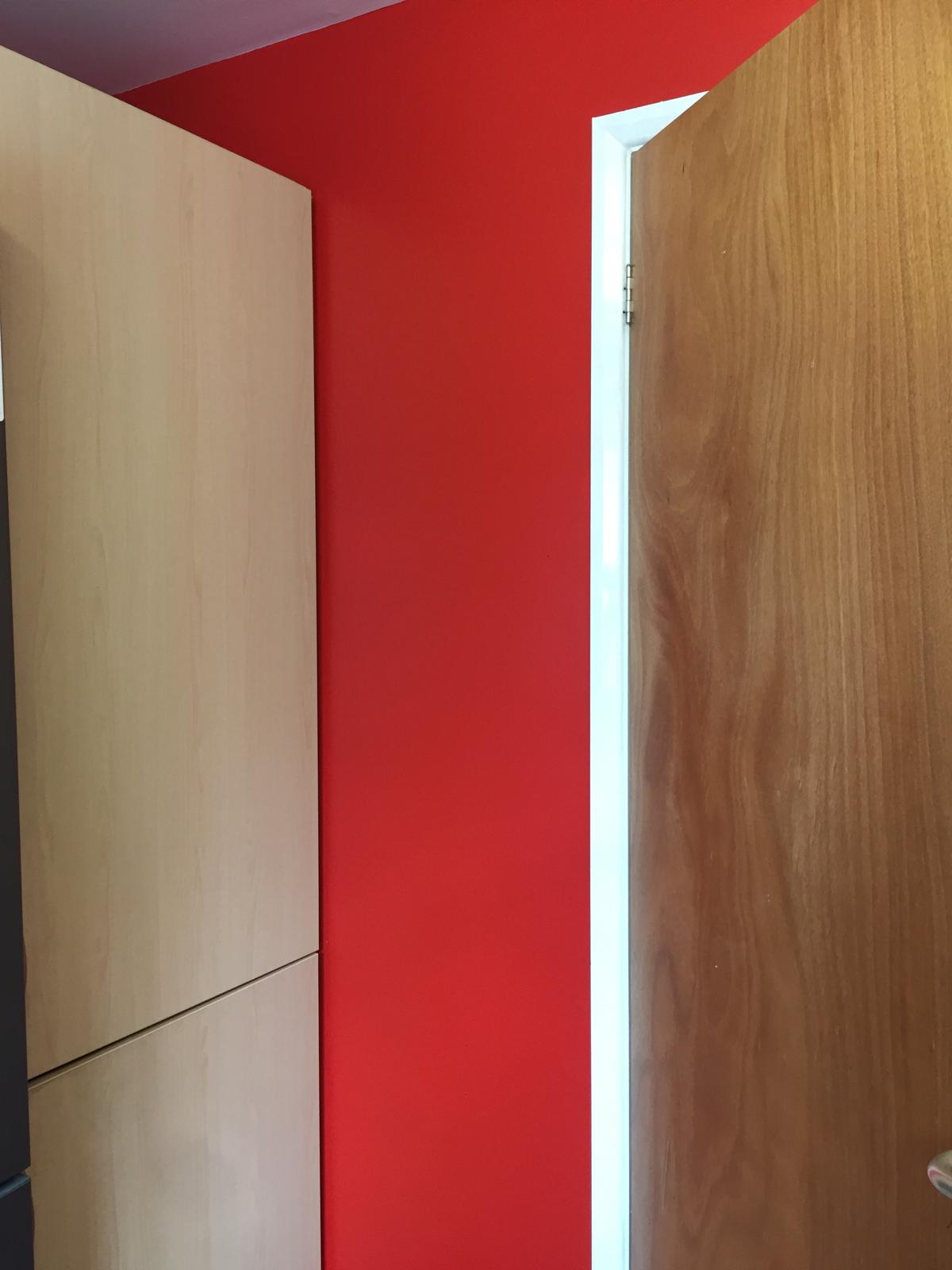 Deep red kitchen wall cut in cleanly against a white door frame