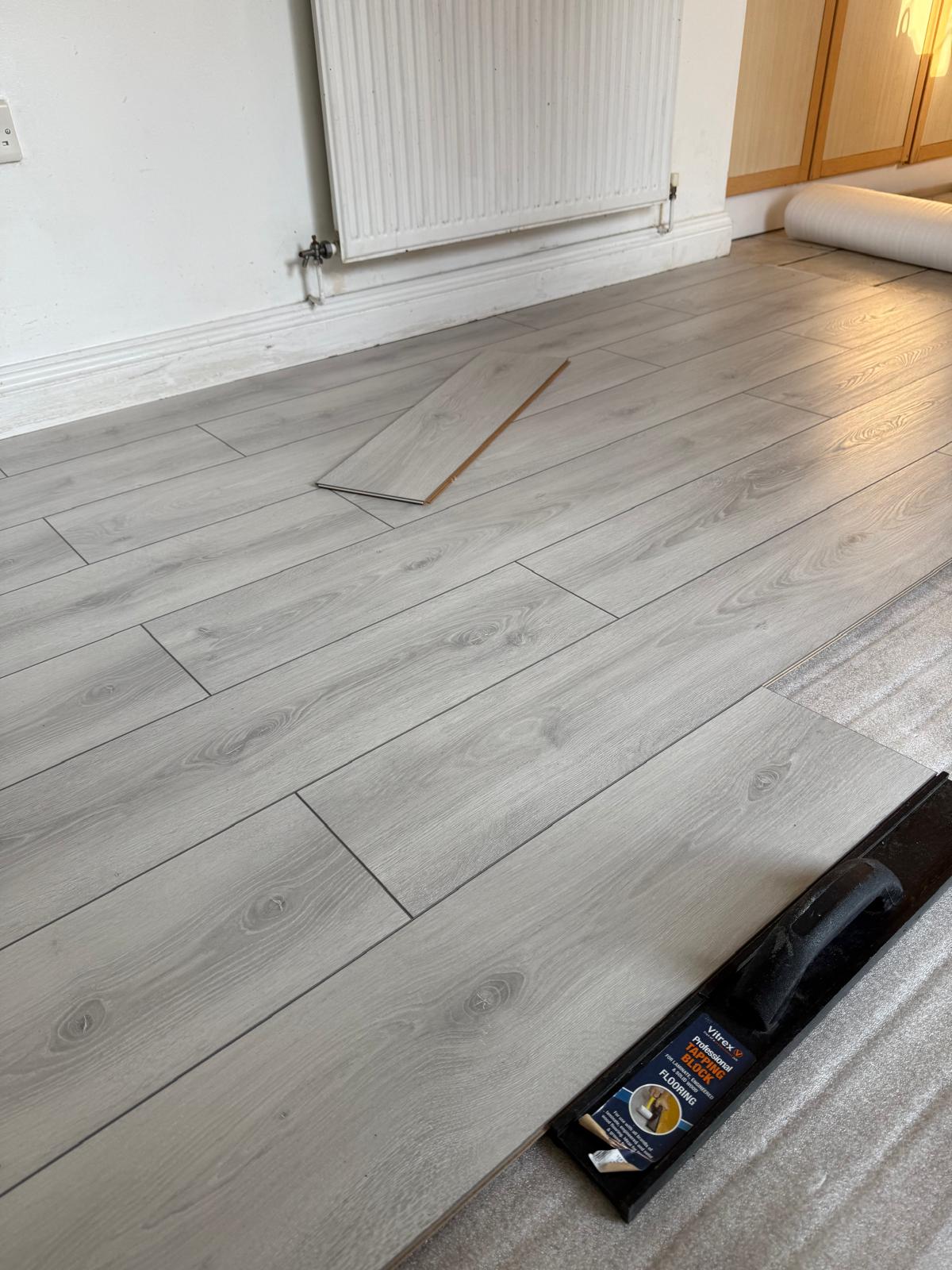 Grey oak laminate part-laid across a living room floor