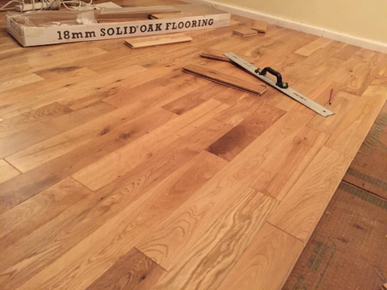 18mm solid oak flooring part-laid with a spirit level resting on the boards